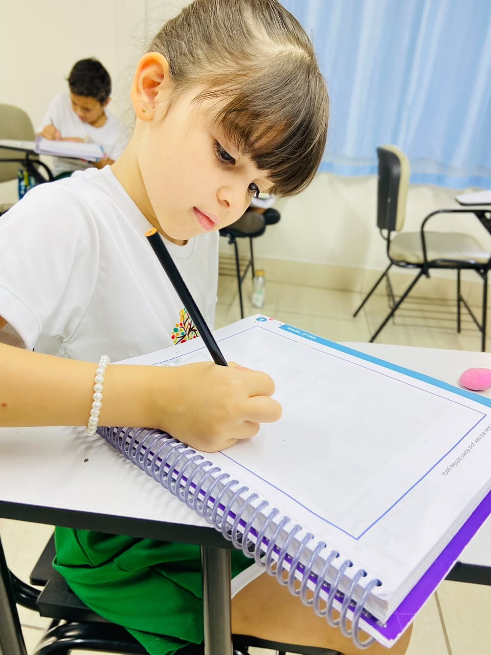 Aluna da Escola Crescer escrevendo em seu caderno
